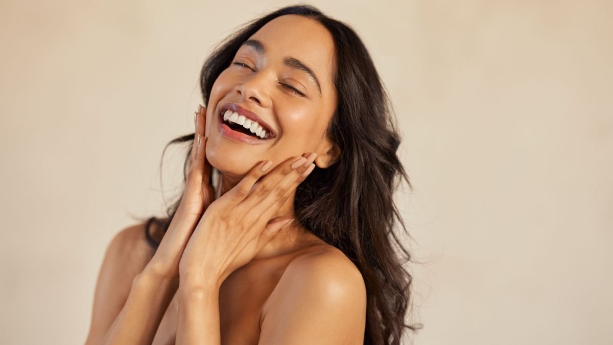 Plusieurs flacons et pots de soin pour le visage élégamment disposés en ordre sur une surface en marbre, illustrant la routine de layering.