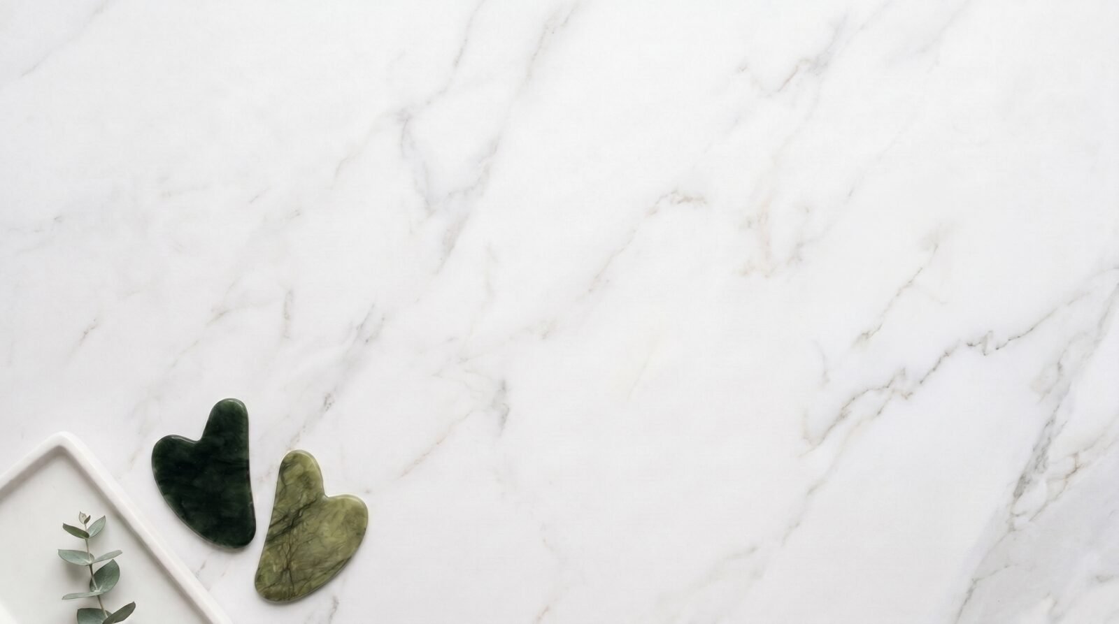 Gua sha jade vert sur marbre blanc avec eucalyptus